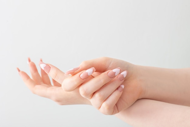 Mãos femininas com lindas unhas compridas com manicure com padrão de coração