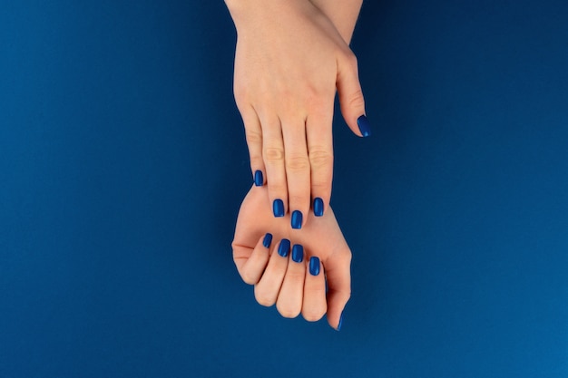 Mãos femininas com manicure de cor azul clássica. Fechar-se