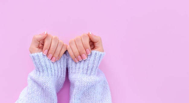 Mãos femininas com manicure francesa em fundo rosa