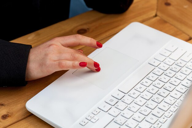 Mãos femininas com manicure vermelha no fundo de um laptop branco