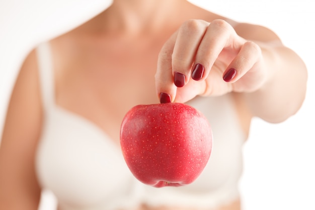 Mãos femininas com manicure vermelho segurando uma maçã vermelha e amarela em um branco