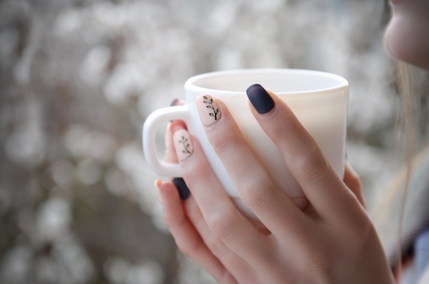 Mãos femininas com uma caneca branca nas mãos