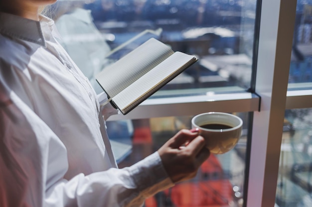 Mãos femininas com uma xícara branca de café americano quente Revigorante café da manhã