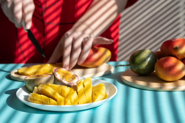 Mãos femininas cortam manga e maracujá, café da manhã de frutas