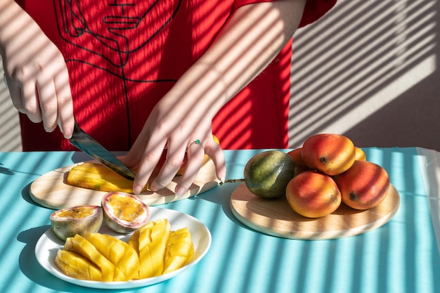 Mãos femininas cortam manga e maracujá, café da manhã de frutas