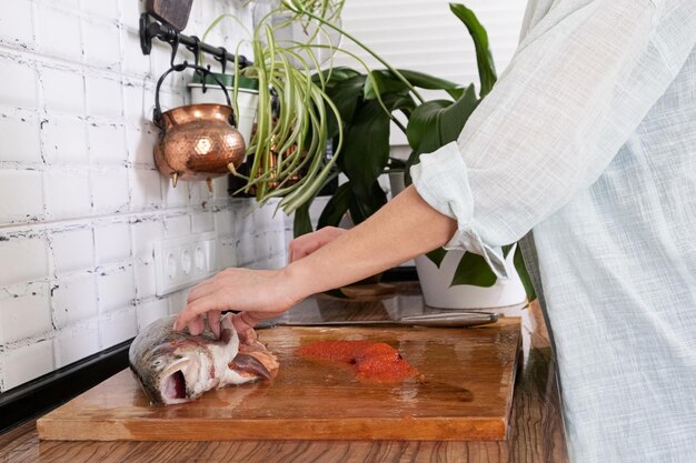 Mãos femininas cortando filé de peixe vermelho Caviar vermelho Removendo espinhas de peixe Massacrando carne de peixe vermelhoxAxAFood concept