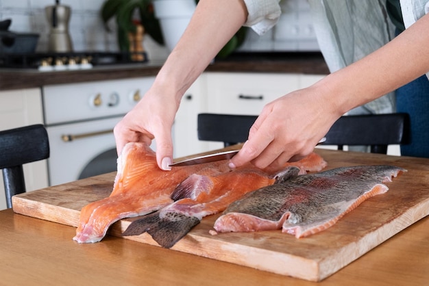 Mãos femininas cortando filé de peixe vermelho Caviar vermelho Removendo espinhas de peixe Massacrando carne de peixe vermelhoxAxAFood concept