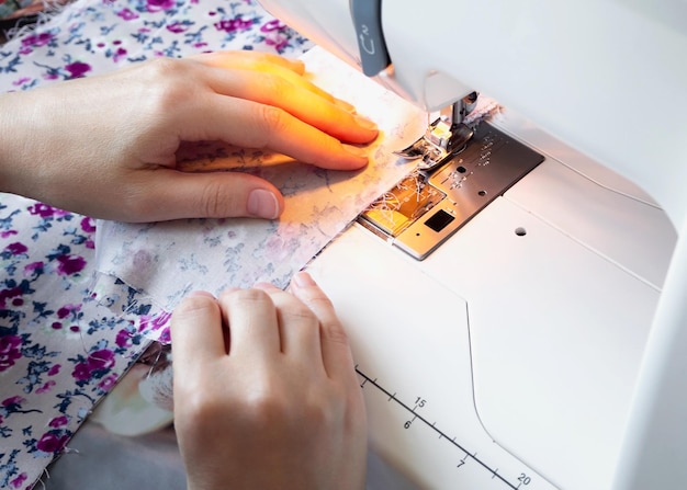 mãos femininas costuram em uma máquina de costura em casa closeup