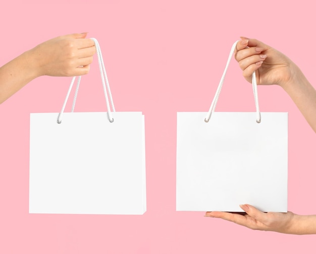 Mãos femininas de maquete seguram um saco de embalagem elegante de papel branco Modelo vazio para seu design e logotipo