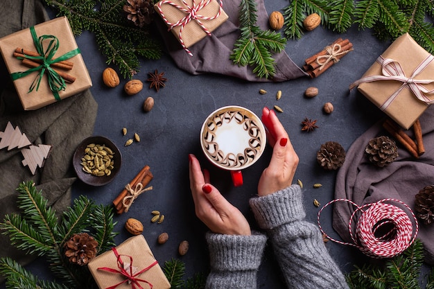 Mãos femininas de natal com caixas de presente e uma xícara de café