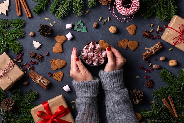 Mãos femininas de Natal com caixas de presente e xícara de chocolate