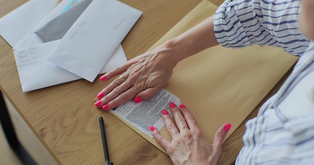 Mãos femininas de perto colocando a carta no formulário de devolução do envelope Mulher envia um formulário de retorno por carta