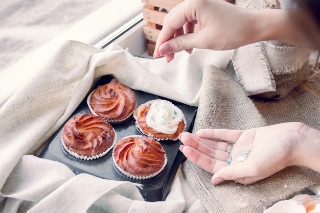 Mãos femininas decoram cupcakes