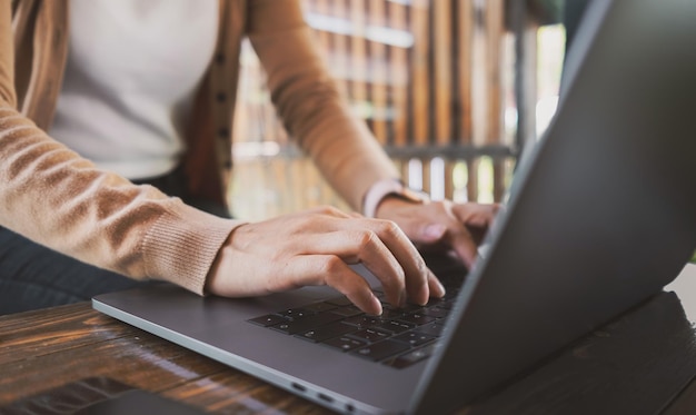 Mãos femininas digitando no laptop enquanto está sentado na mesa do escritório dentro de casa conversando no facebook pesquisando informações de navegação conceito de tecnologia