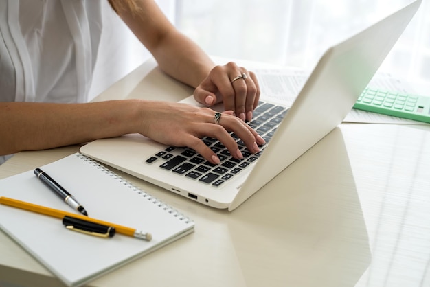 Mãos femininas digitando no teclado do laptop de perto