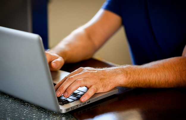 Mãos femininas digitando no teclado do laptop no escritório, em casa