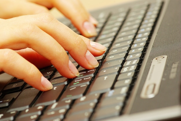 Mãos femininas digitando no teclado do laptop