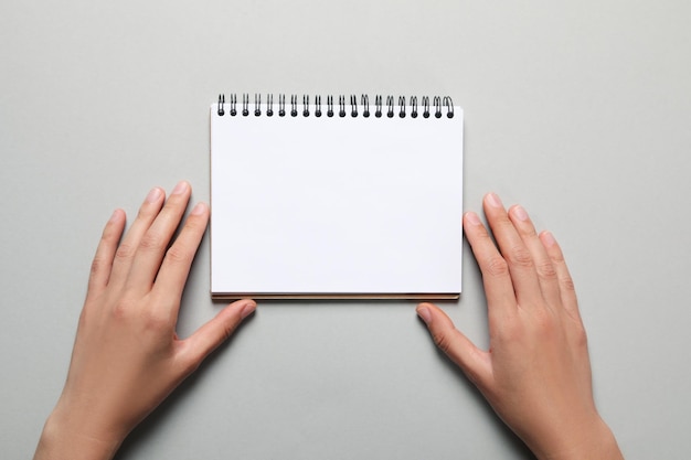 Foto mãos femininas e caderno em branco sobre fundo cinza claro