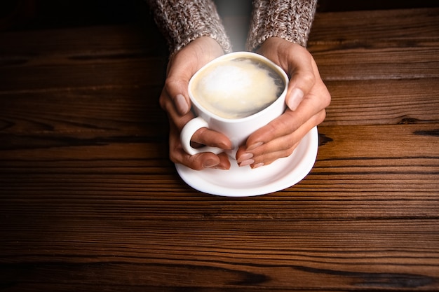 Mãos femininas e café em fundo de madeira