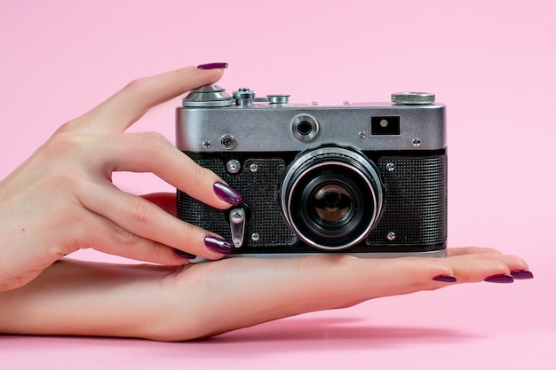 Foto mãos femininas e câmera em fundo rosa