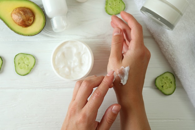 Mãos femininas e cosméticos naturais em uma mesa de madeira branca