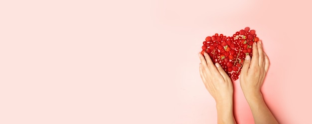 Mãos femininas e frutas vermelhas em forma de coração