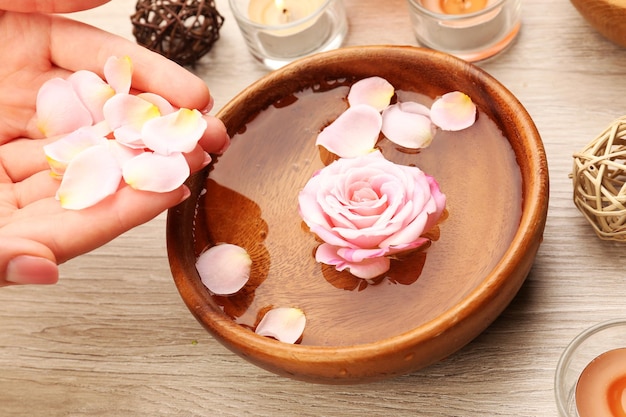 Mãos femininas e tigela de água termal com flores closeup