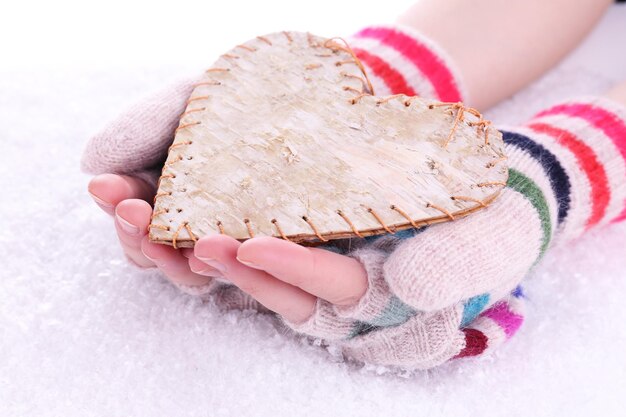 Mãos femininas em luvas com coração em fundo de neve