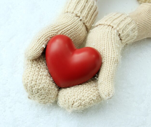 Mãos femininas em luvas com coração vermelho, close-up