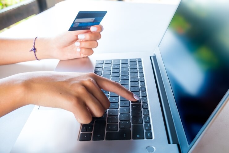Foto mãos femininas em um teclado e segurando um cartão de crédito para fazer compras no site de comércio eletrônico