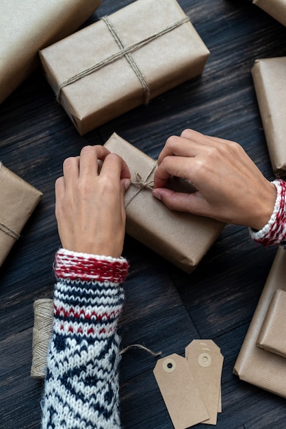 Mãos femininas envolvendo caixa de presente de Natal
