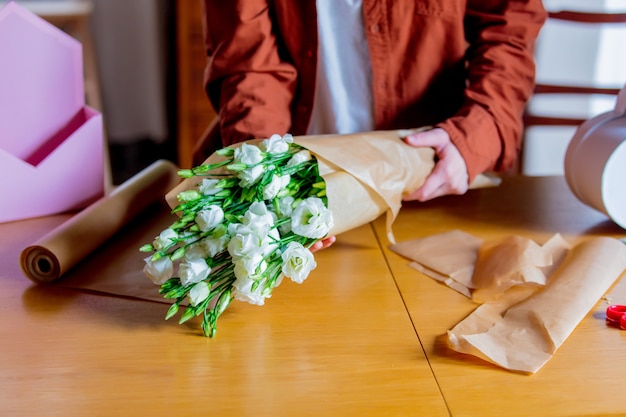 Mãos femininas envolvendo um rosas brancas e papel