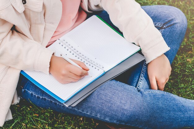 Mãos femininas escrevem em um caderno.