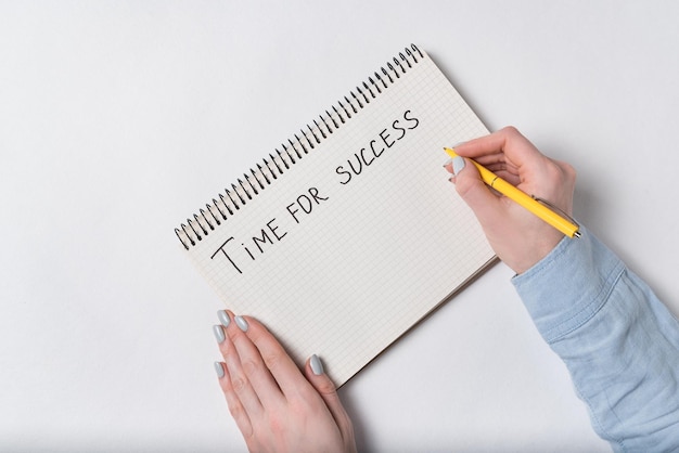 Mãos femininas escrevem no bloco de notas TIME FOR SUCCESS Fundo branco