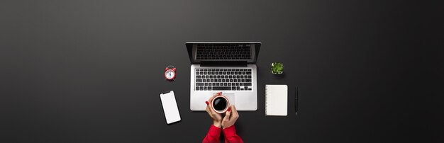 Mãos femininas estão trabalhando em um laptop moderno. Mesa preta com um lugar para sua inscrição