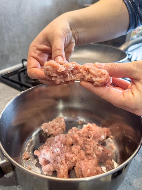 Mãos femininas fazem almôndegas com carne picada de gordura vermelha de perto