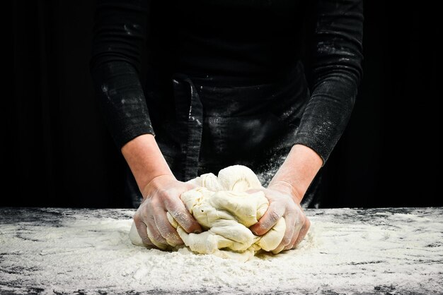 Mãos femininas fazendo massa para pão com respingo de farinha Fundo de cozinha