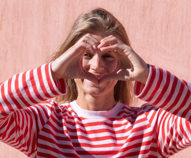 Mãos femininas fazendo o sinal coração com os dedos