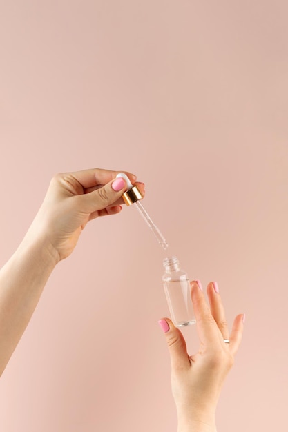 Mãos femininas gotejando óleo com uma pipeta dentro de um gotero com um produto de cuidados