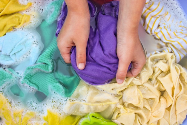 Mãos femininas lavar roupas coloridas na bacia.