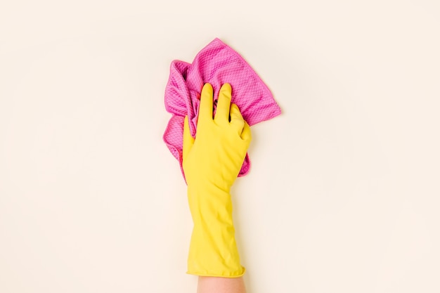 Mãos femininas limpando em fundo amarelo pálido. Fundo de conceito de limpeza ou arrumação. Copie o espaço. Postura plana, vista superior.