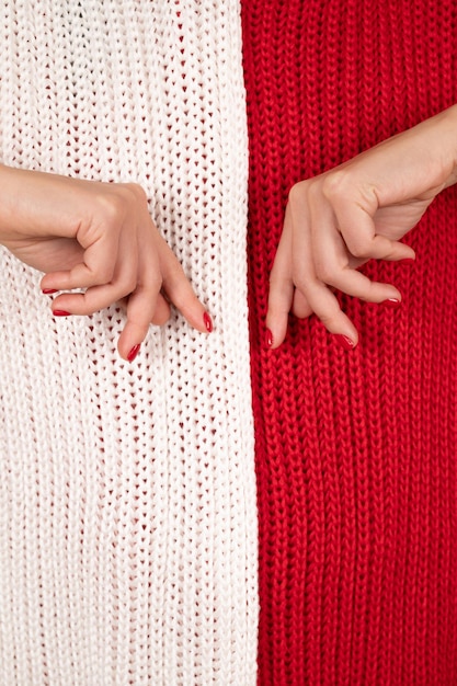 Mãos femininas macias fecham a vista sobre fundo de malha branco e vermelho Conceito de manicure de inverno