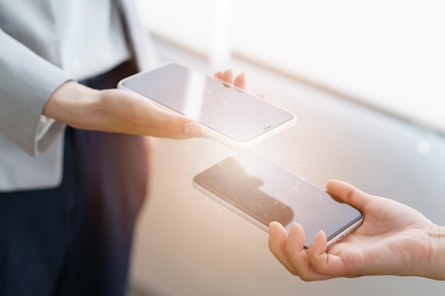 Mãos femininas mostrando uma à outra a tela do smartphone