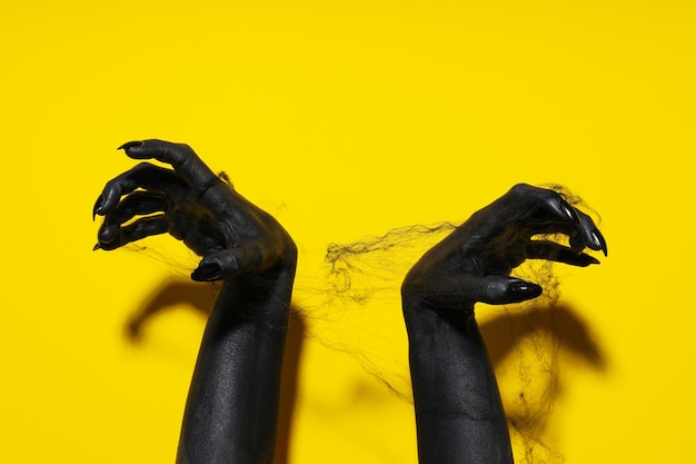 Mãos femininas negras em teia de aranha em fundo amarelo