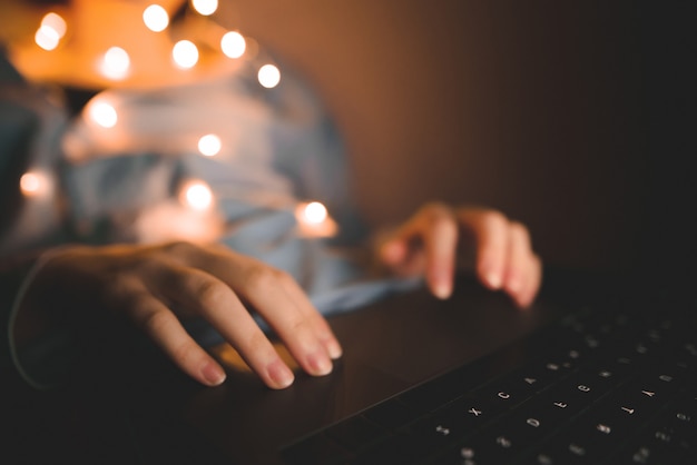 Foto mãos femininas no laptop, a mão da garota trabalha à noite no gadget.