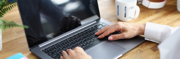 Mãos femininas no teclado do laptop na mesa de trabalho no escritório