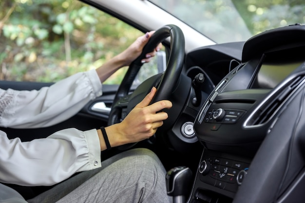 Mãos femininas no volante de um carro. Mulher motorista, interior do carro