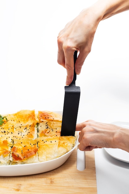 Mãos femininas pegando o pedaço de torta grega spanakopita Comida vegana caseira