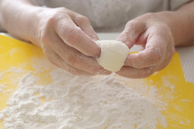 Mãos femininas preparam massa para tortas ou pães na mesa closeup