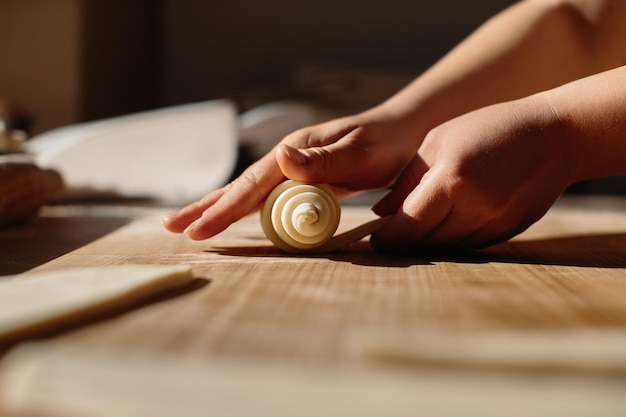 Mãos femininas rolando massa no processo de cozimento de rolos, fazendo croissant selecionado conceito de foco para padaria